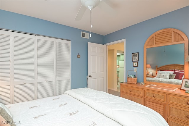 bedroom with a ceiling fan, freestanding refrigerator, a closet, and visible vents