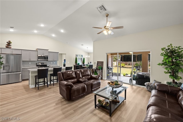 living area with ceiling fan with notable chandelier, high vaulted ceiling, light wood-style flooring, and visible vents