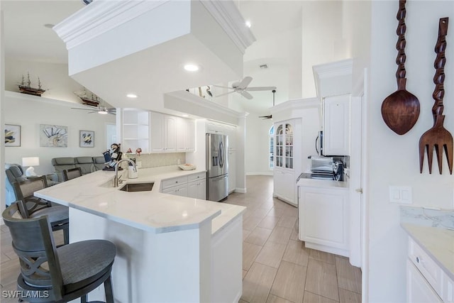 kitchen featuring a breakfast bar, appliances with stainless steel finishes, a sink, ceiling fan, and a peninsula