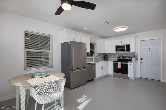 kitchen featuring visible vents, stainless steel appliances, light countertops, white cabinetry, and backsplash