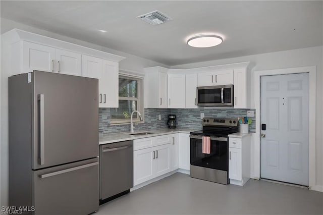 kitchen with appliances with stainless steel finishes, light countertops, a sink, and white cabinetry