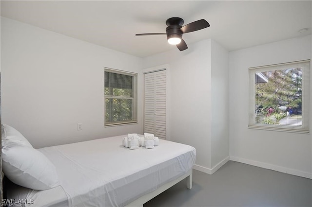 bedroom featuring a ceiling fan, finished concrete floors, and baseboards