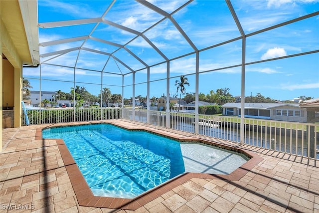 pool with glass enclosure, a patio, and a water view