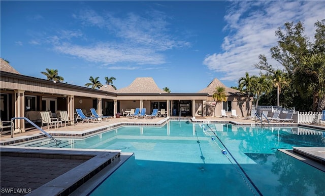 community pool with a patio area and fence