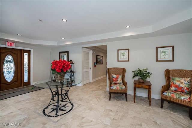 foyer entrance with baseboards, a raised ceiling, and recessed lighting