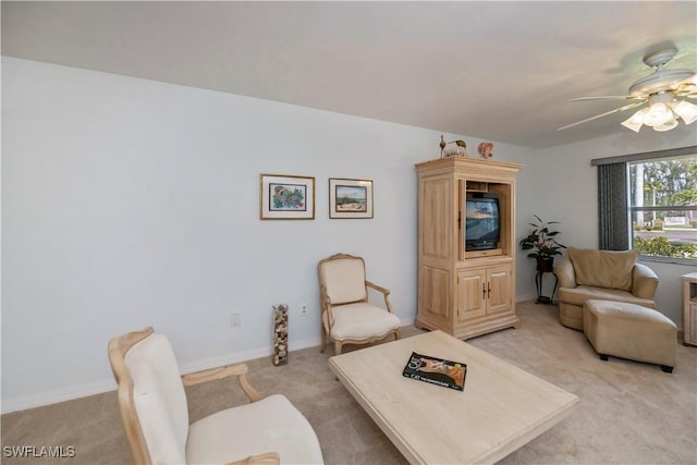 living area with light carpet, ceiling fan, and baseboards