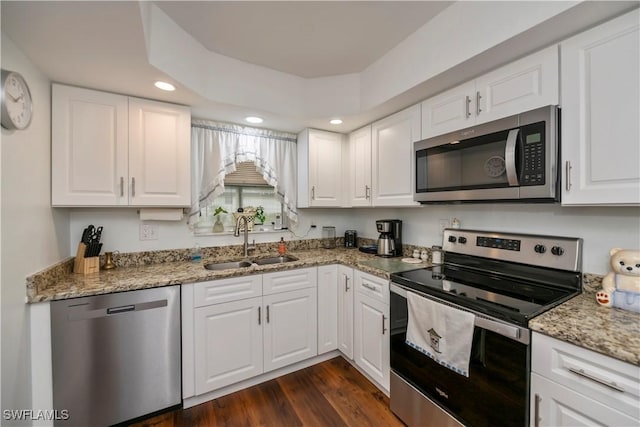 kitchen featuring light stone counters, dark wood-style flooring, a sink, white cabinetry, and appliances with stainless steel finishes