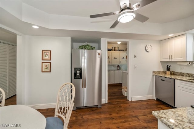 kitchen featuring dark wood-style floors, appliances with stainless steel finishes, white cabinetry, light stone countertops, and baseboards