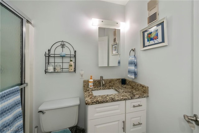 bathroom with a shower stall, vanity, and toilet