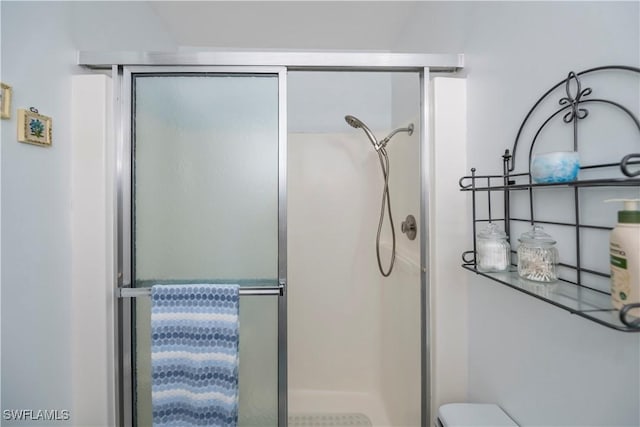 bathroom featuring toilet and a stall shower