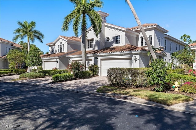 mediterranean / spanish home featuring a garage, a tiled roof, decorative driveway, and stucco siding