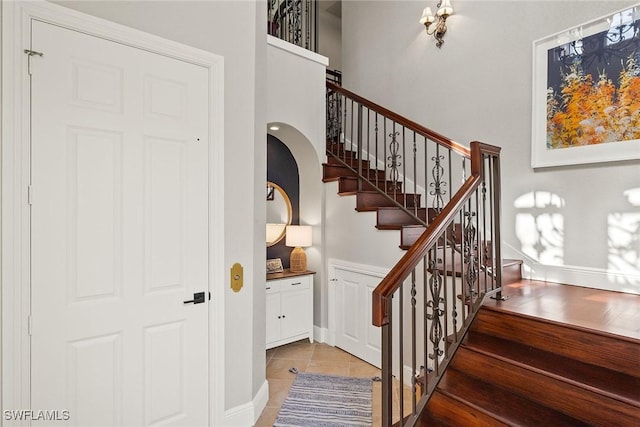 stairway featuring tile patterned flooring and a high ceiling