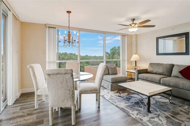 dining area with a wall of windows, ceiling fan with notable chandelier, baseboards, and wood finished floors