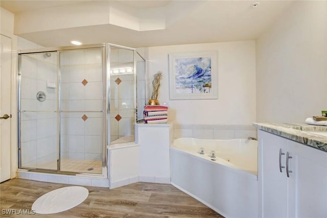 full bath featuring a stall shower, vanity, a bath, and wood finished floors