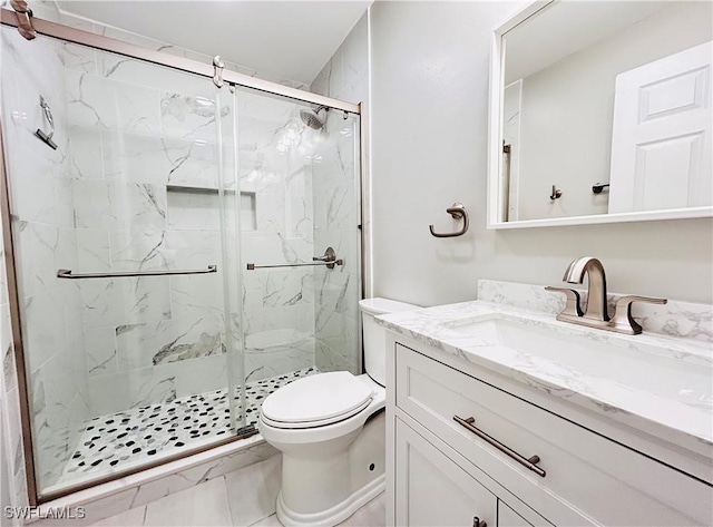 full bath featuring a marble finish shower, vanity, and toilet