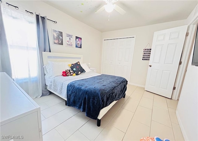 bedroom with a ceiling fan, light tile patterned floors, baseboards, and a closet