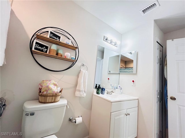 bathroom with toilet, vanity, and visible vents