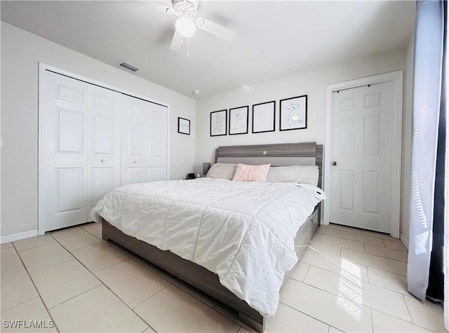 bedroom featuring a closet, visible vents, light tile patterned flooring, ceiling fan, and baseboards