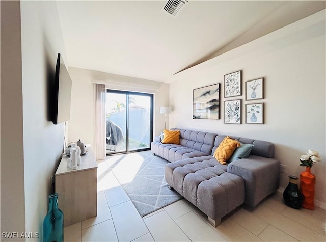 living area with lofted ceiling, visible vents, and light tile patterned floors