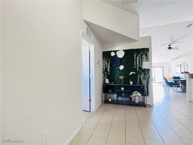 hallway with visible vents, baseboards, and light tile patterned floors