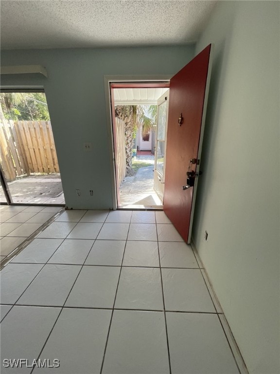 doorway with light tile patterned floors and a textured ceiling