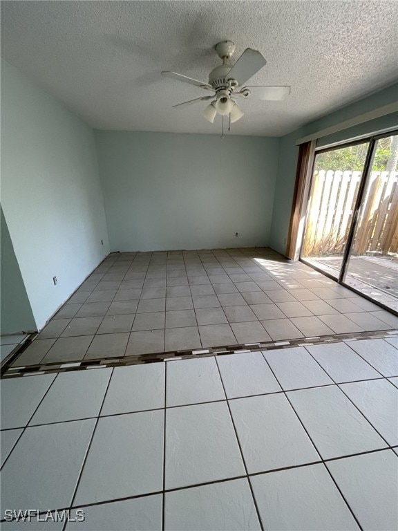 spare room with light tile patterned floors, ceiling fan, and a textured ceiling