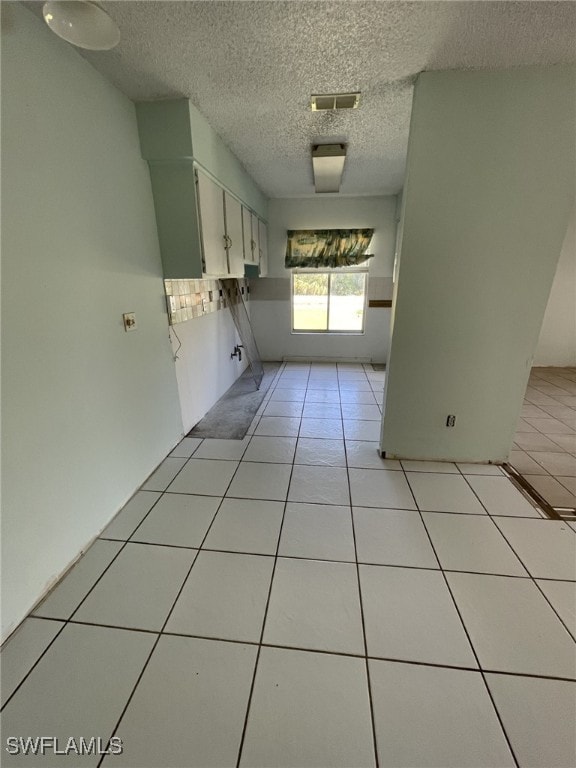 kitchen featuring visible vents, white cabinetry, a textured ceiling, and light tile patterned flooring