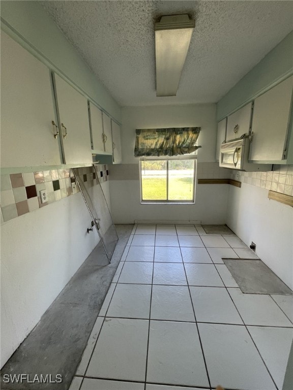 laundry area featuring a textured ceiling and light tile patterned flooring