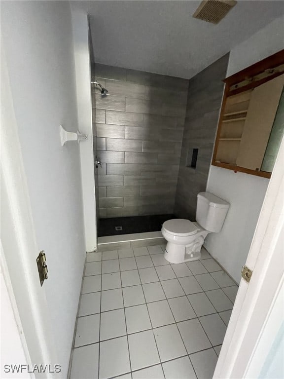 full bathroom with a stall shower, tile patterned flooring, visible vents, and toilet