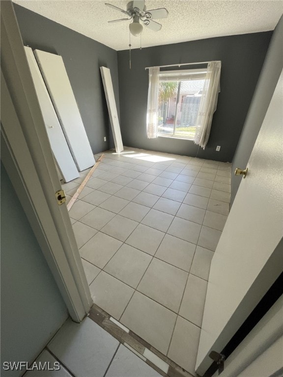 spare room with a ceiling fan, a textured ceiling, and light tile patterned flooring