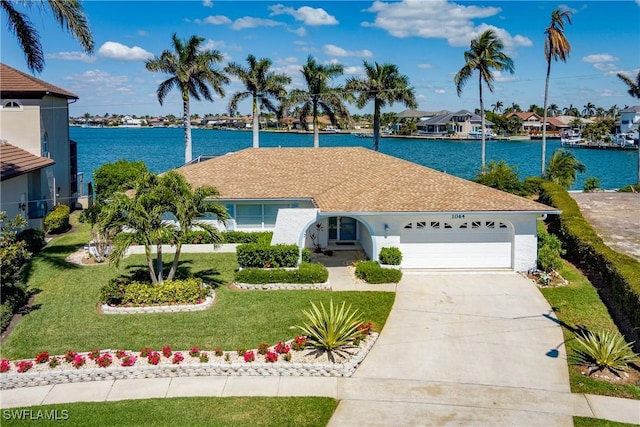 ranch-style house featuring an attached garage, a water view, concrete driveway, a residential view, and a front lawn