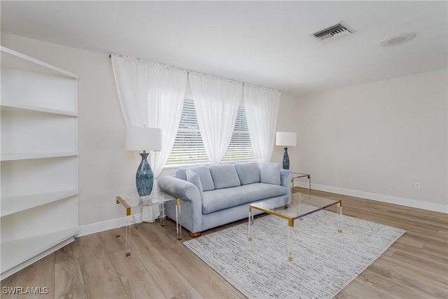 living room featuring baseboards, visible vents, and wood finished floors