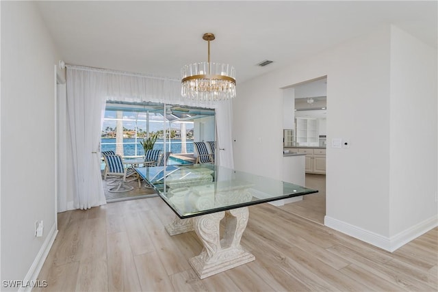 unfurnished dining area with a chandelier, light wood finished floors, visible vents, and baseboards