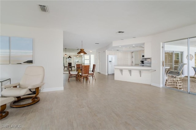 living area featuring light wood-style flooring, visible vents, and baseboards