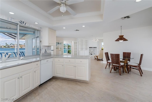 kitchen featuring a tray ceiling, visible vents, white dishwasher, light wood-type flooring, and a peninsula