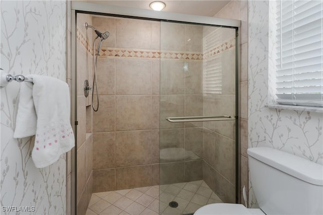 bathroom with a stall shower, toilet, and wallpapered walls