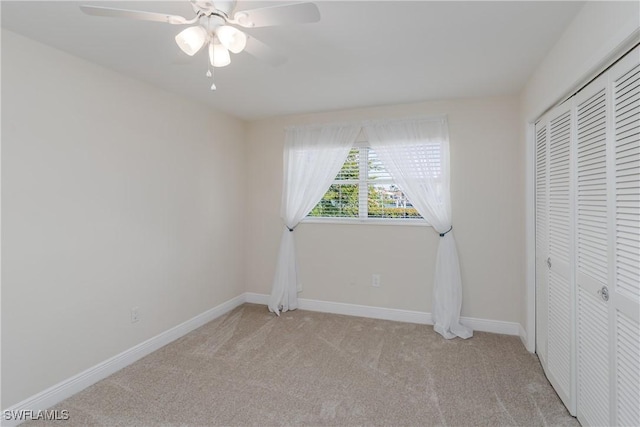 unfurnished bedroom with light carpet, ceiling fan, a closet, and baseboards