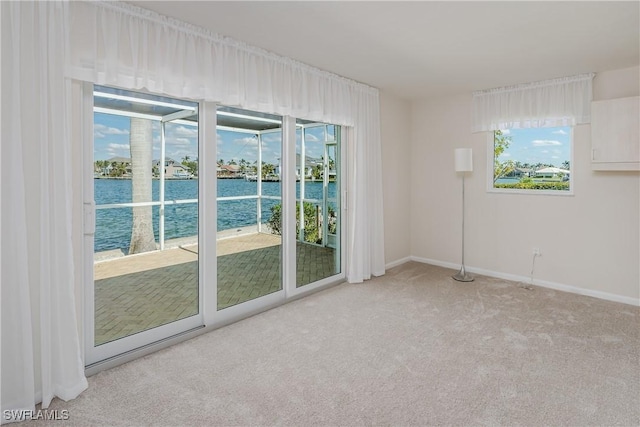 carpeted spare room featuring a water view and baseboards