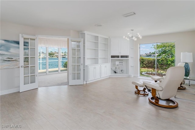 living area with light wood-style flooring, visible vents, a notable chandelier, and french doors