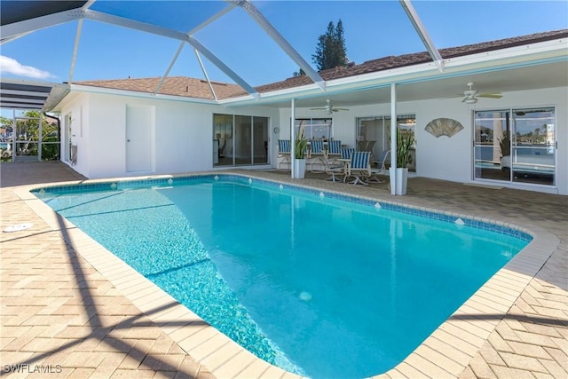 outdoor pool featuring a patio, glass enclosure, and a ceiling fan