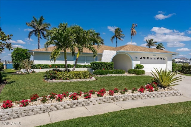 ranch-style house featuring a garage, a front yard, driveway, and stucco siding