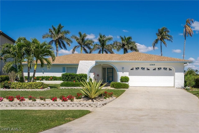 ranch-style home featuring an attached garage, concrete driveway, and stucco siding