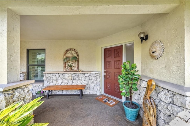 property entrance featuring stone siding and stucco siding