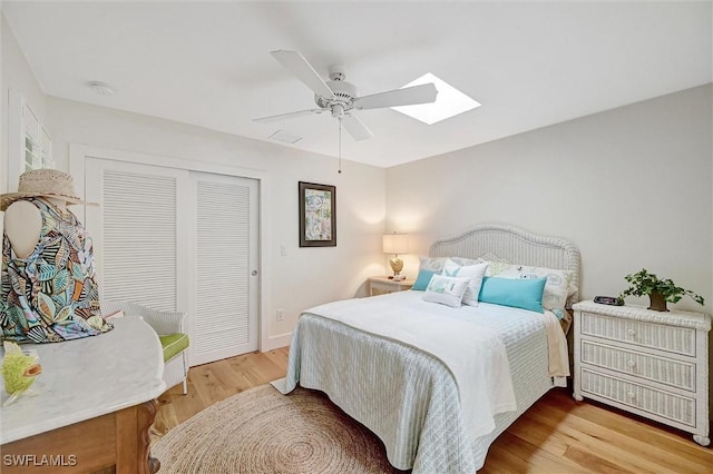 bedroom featuring ceiling fan, a closet, a skylight, and wood finished floors