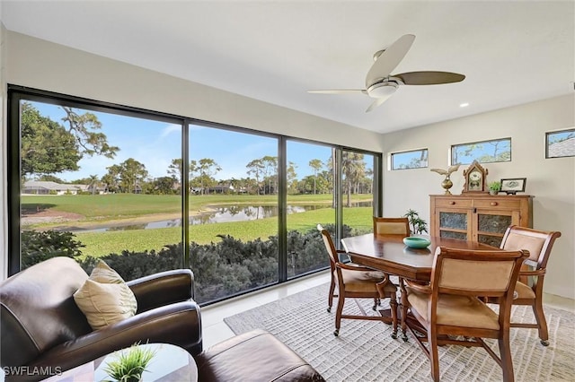 sunroom featuring a water view and ceiling fan