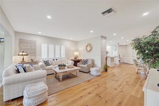 living room with light wood finished floors, visible vents, and recessed lighting