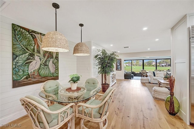 dining space featuring recessed lighting, wood walls, and light wood-style flooring