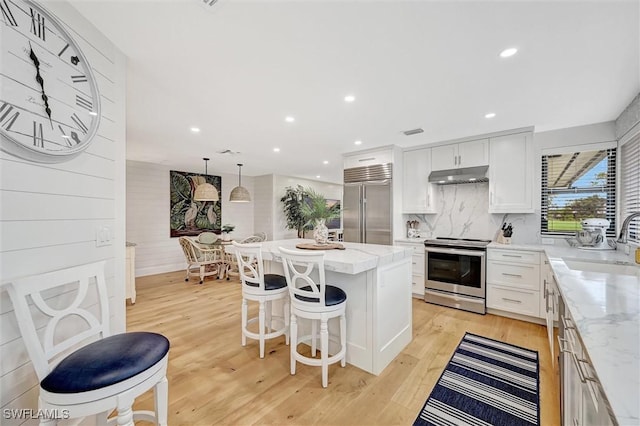 kitchen featuring stainless steel appliances, a kitchen island, under cabinet range hood, and white cabinets