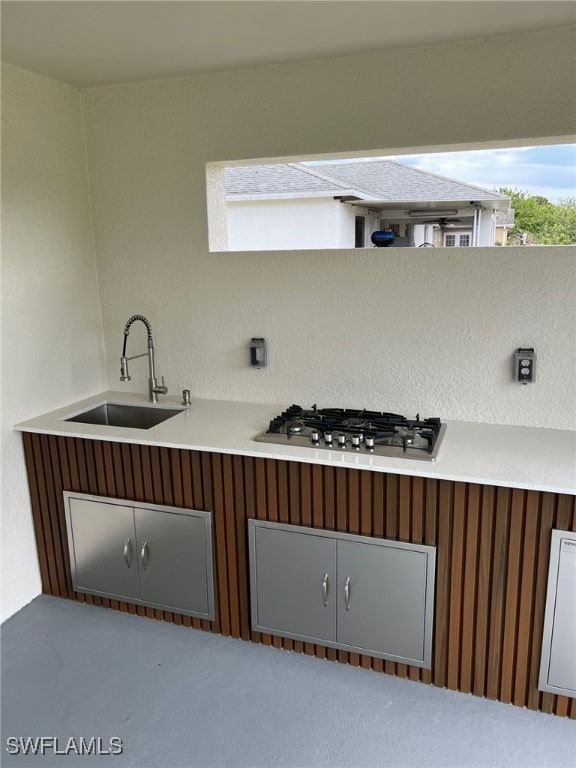 kitchen with stainless steel gas stovetop, light countertops, and a sink