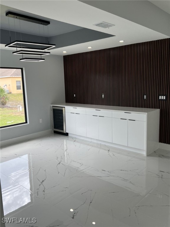 bar with marble finish floor, visible vents, and beverage cooler